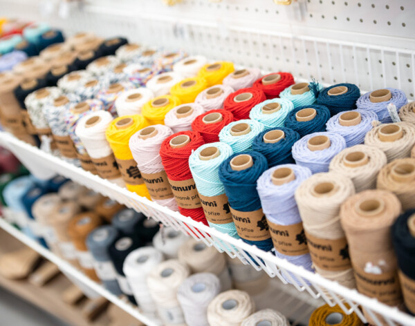 Colorful spools of thread and yarn organized on white retail shelf display