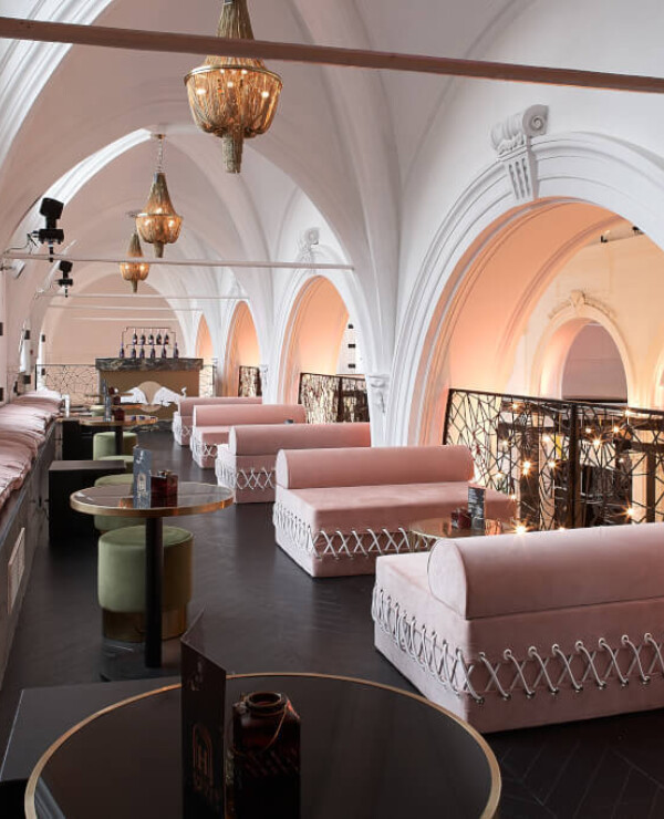 Horeca lounge interior with barrel seating, arched white ceilings, brass pendant lights and decorative railings