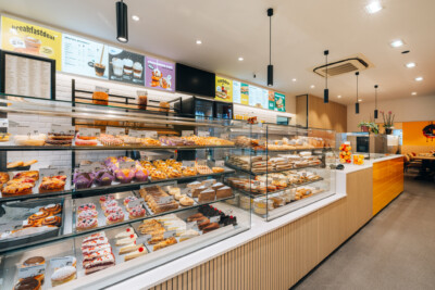 Modern bakery display with multi-tier glass showcases featuring pastries, cakes and baked goods in refrigerated counters