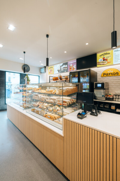 Panos bakery shopfront with Pitch 25 shelving displaying bread, pastries and baked goods in curved glass display counter