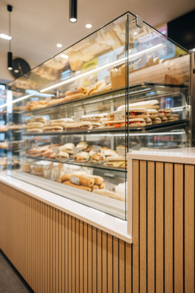 Curved glass display counter with multiple shelves of baked goods and pastries in bakery retail setting