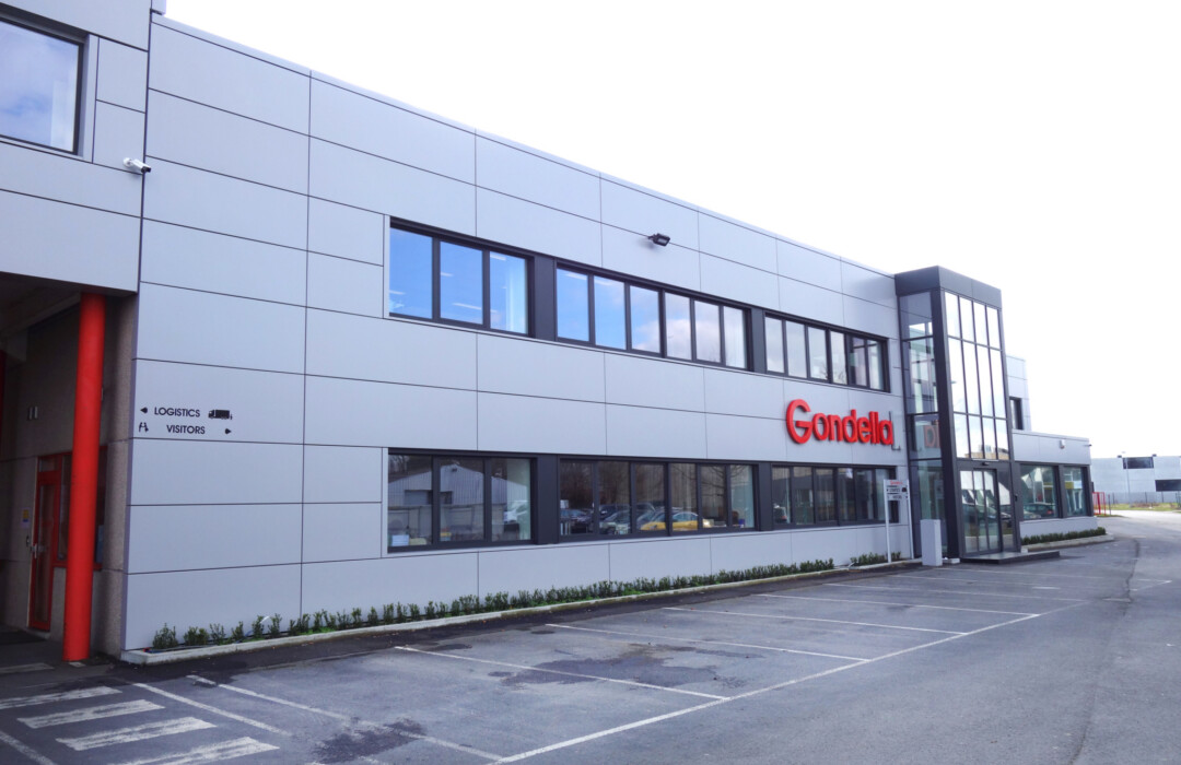 Gondella manufacturing facility exterior with white facade panels and red entrance