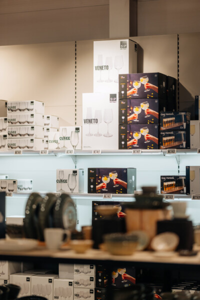 Gondola shelving displaying glassware product boxes including Veneto wine glasses, Cuvee champagne flutes, and cocktail gift sets in retail store setup