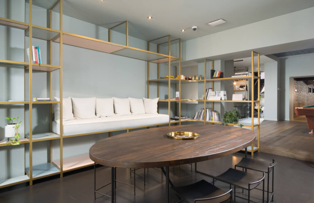 Modern office showroom with Pitch 25 shelving system, white sofa, and wooden oval table