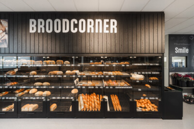 Broodcorner bakery display with Pitch shelving system showcasing bread, baguettes and rolls in black glass-fronted gondola