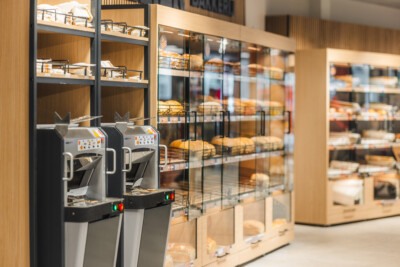 Carrefour Market checkout counter with dual coffee machines and shelving display in bakery section