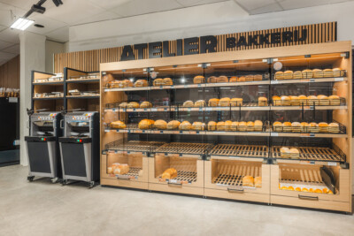 Artisan bakery display with illuminated shelving, bread products, and self-checkout terminals in Carrefour Market