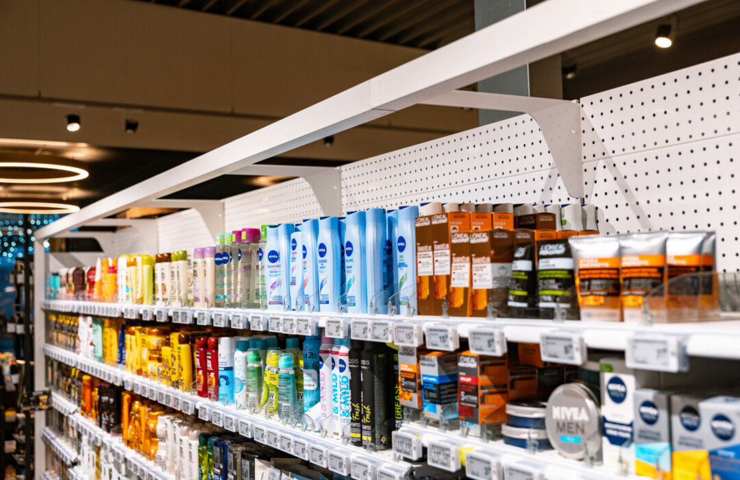 Health and beauty products displayed on multi-shelf retail gondola with Nivea bottles, spray bottles, and boxed items across three shelves