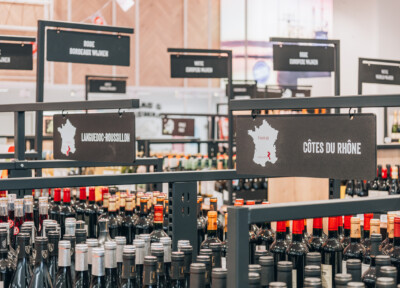 Wine retail display with Languedoc-Roussillon and Côtes du Rhône signage, custom shelving with bottles and price labels