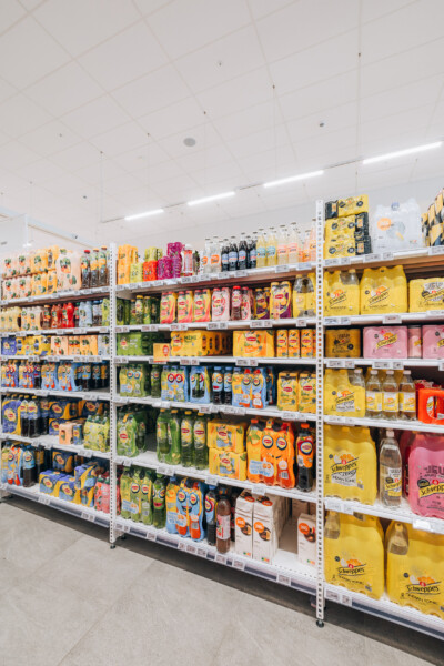 Delhaize beverage section with Pitch 41 shelving displaying juices, soft drinks and water bottles
