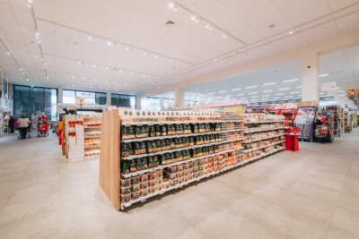 Delhaize supermarket interior with Pitch 25 shelving displaying packaged goods and beverages in organized retail layout