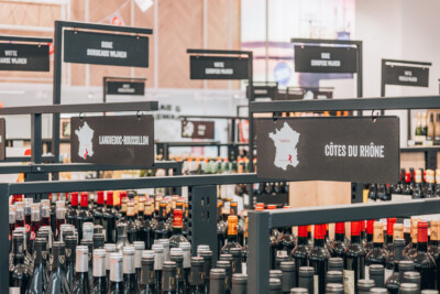 Wine retail display with Languedoc-Roussillon and Côtes du Rhône signage, custom shelving with bottles and price labels