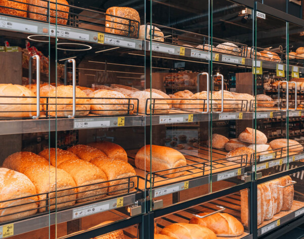 Delhaize bakery display with multi-tier glass shelving showcasing fresh bread and rustic loaves