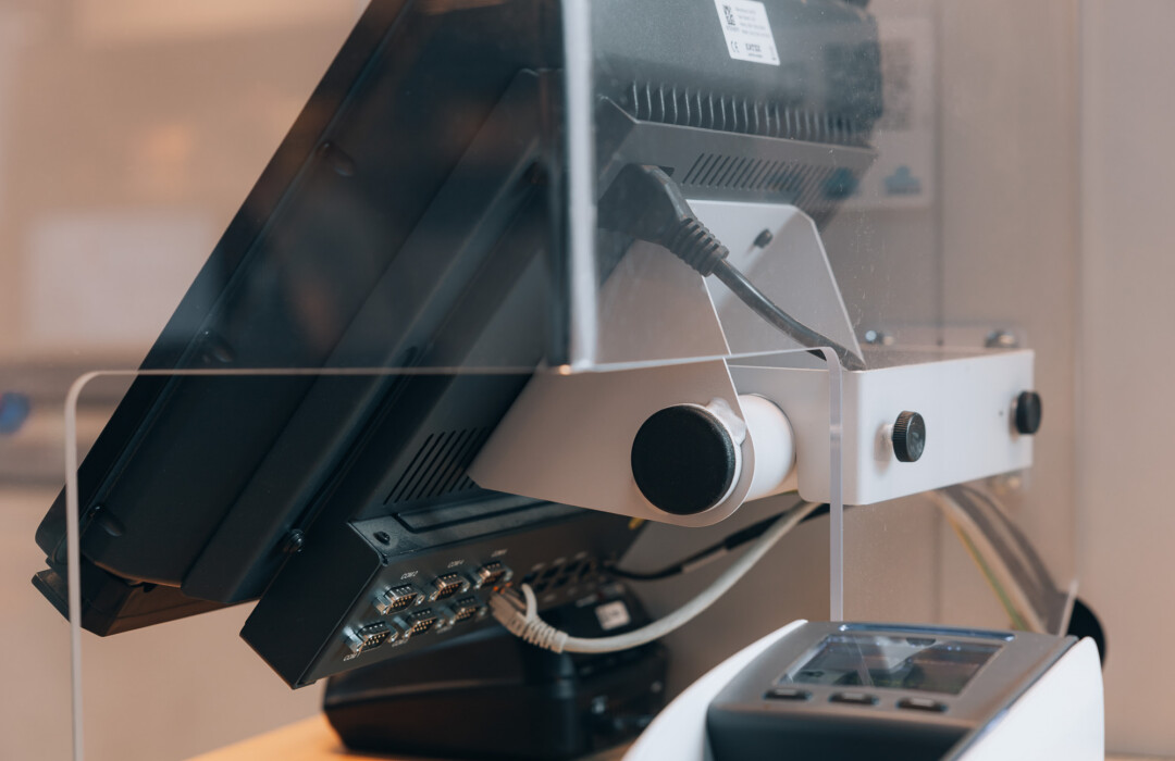 White retail camera mount with black lens attached to display monitor, showcasing security and surveillance solution for retail environments