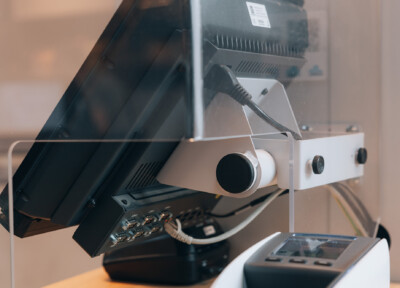 White retail camera mount with black lens attached to display monitor, showcasing security and surveillance solution for retail environments