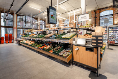 Delhaize supermarket produce section with Gondella tiered shelving displaying fresh vegetables and fruits