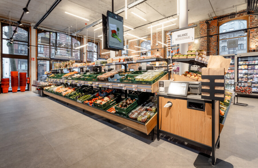 Delhaize supermarket produce section with Gondella tiered shelving displaying fresh vegetables and fruits