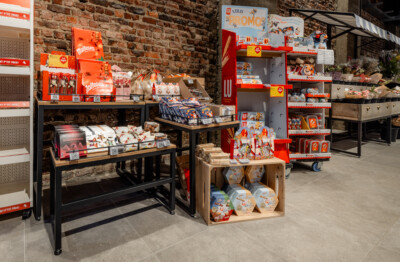 Lulu branded retail display with Maltesers and Kinder products on black shelving, wooden fixtures and red promotional stands in supermarket setting