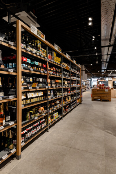 Wooden-framed shelving display with packaged beverages and food products in modern supermarket aisle