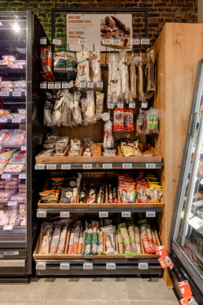 Specialty food display with dry sausages, cured meats and charcuterie hanging from hooks on wooden shelving with multiple tiers