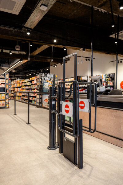 Entrance gates with no-entry signs at Proxy Delhaize supermarket, shelving displays visible in background