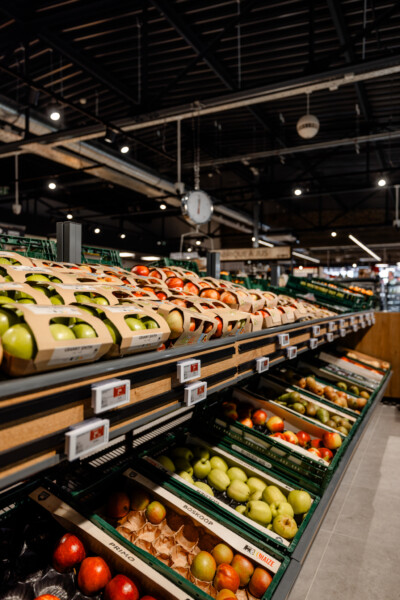 Pitch 25 shelving displaying packaged apples and mixed fruit in green retail crates at Delhaize supermarket
