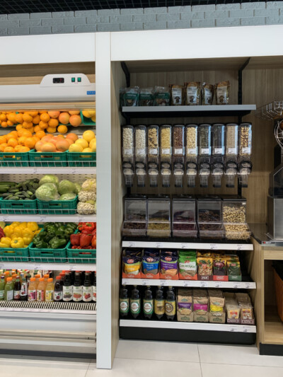 Specialty food display with bulk dispensers, dry goods containers, and packaged products on wooden shelving