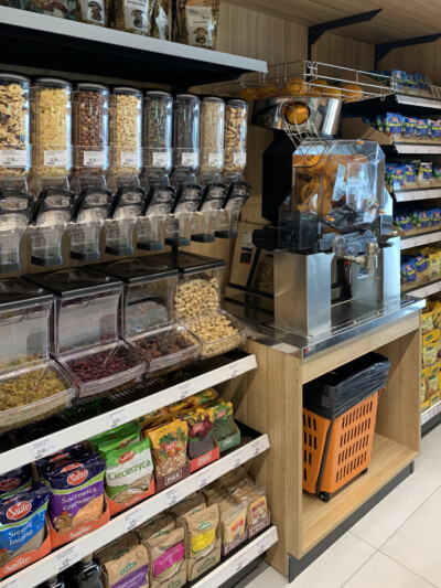 Specialty food retail display with bulk cereal dispensers, packaged goods shelving, and popcorn machine in Metro supermarket