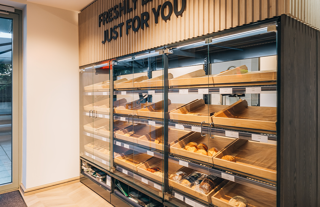 Wooden bakery display case with glass doors showing fresh bread and pastries on multiple shelves