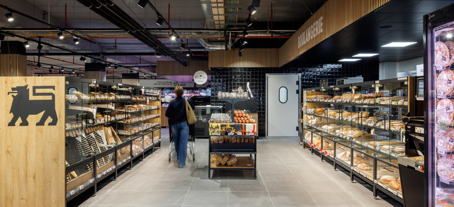 Delhaize bakery section with Pitch shelving displaying bread and pastries in modern supermarket layout
