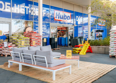 Hubo DIY store exterior display with outdoor furniture, building materials stacks, and yellow playground slide