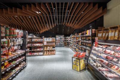 Delhaize supermarket meat and grocery section with Pitch shelving, refrigerated displays, and wooden ceiling design