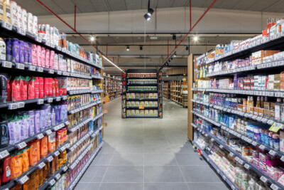 Delhaize supermarket aisle with Gondella shelving displaying health and beauty products in pink, purple, and orange packaging