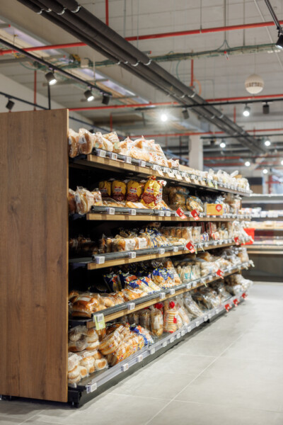 Delhaize bakery section with Pitch 25 shelving displaying packaged bread and baked goods across six shelves