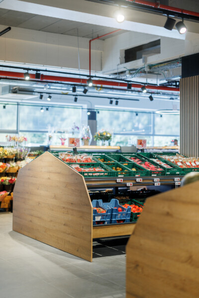 Delhaize supermarket produce section with Gondella wooden display stand and green crates of fresh vegetables