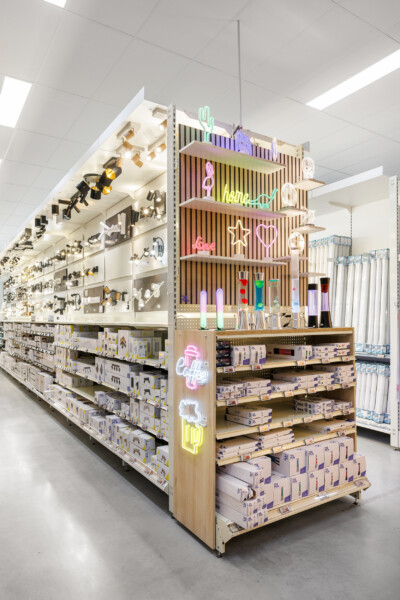 Health and beauty retail display with Pitch shelving, neon signage, and wooden slatted gondola featuring packaged products and cosmetic items