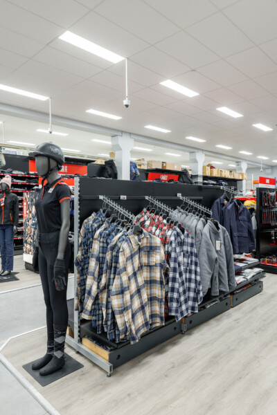 Fashion retail display with black clothing mannequin and plaid shirt gondola in modern store