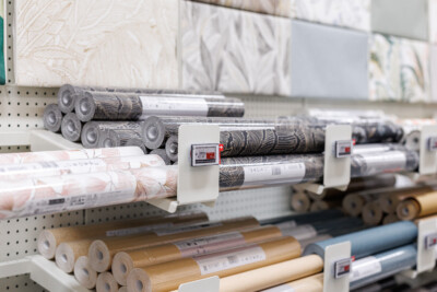 Rolled wallpaper and fabric samples on retail display shelf with price labels