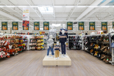 Retail store interior with mannequins displaying knitwear and clothing, Pitch shelving with Christmas decorations and footwear displays