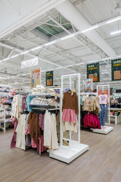 Children's clothing display with white Pitch shelving and hanging rails in fashion retail environment