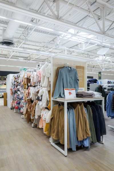 Fashion retail clothing display with Pitch shelving unit showing folded garments and hanging apparel in neutral tones