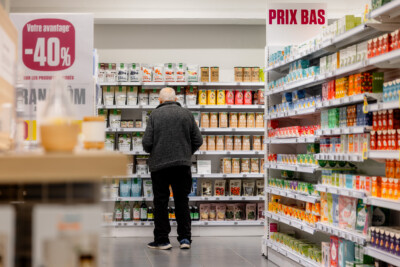 Elderly customer browsing Pitch shelving displaying branded food products in supermarket aisle with 40% discount signage