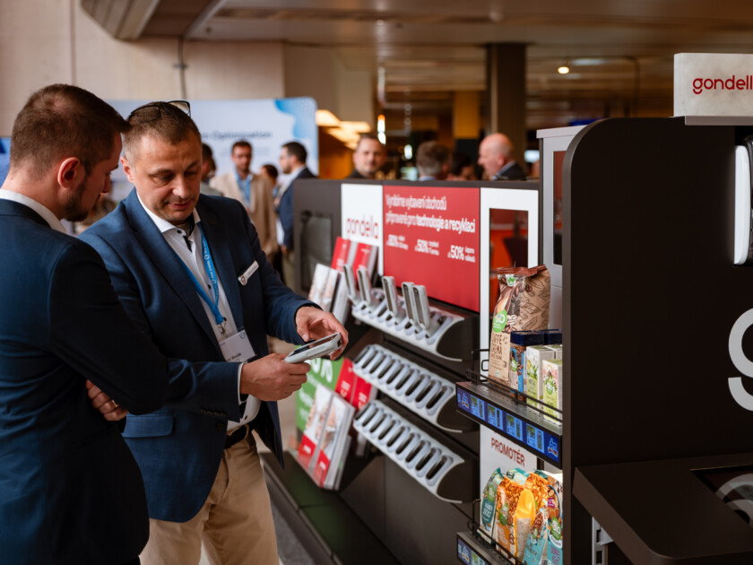 Two professionals examining Gondella retail display at trade show with shelving and products